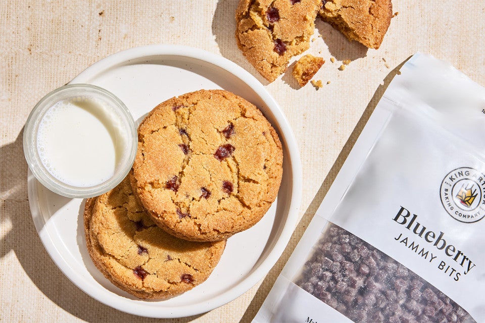 A couple of Peanut Butter and Jelly Cookies on a plate next to a bag of jammy bits