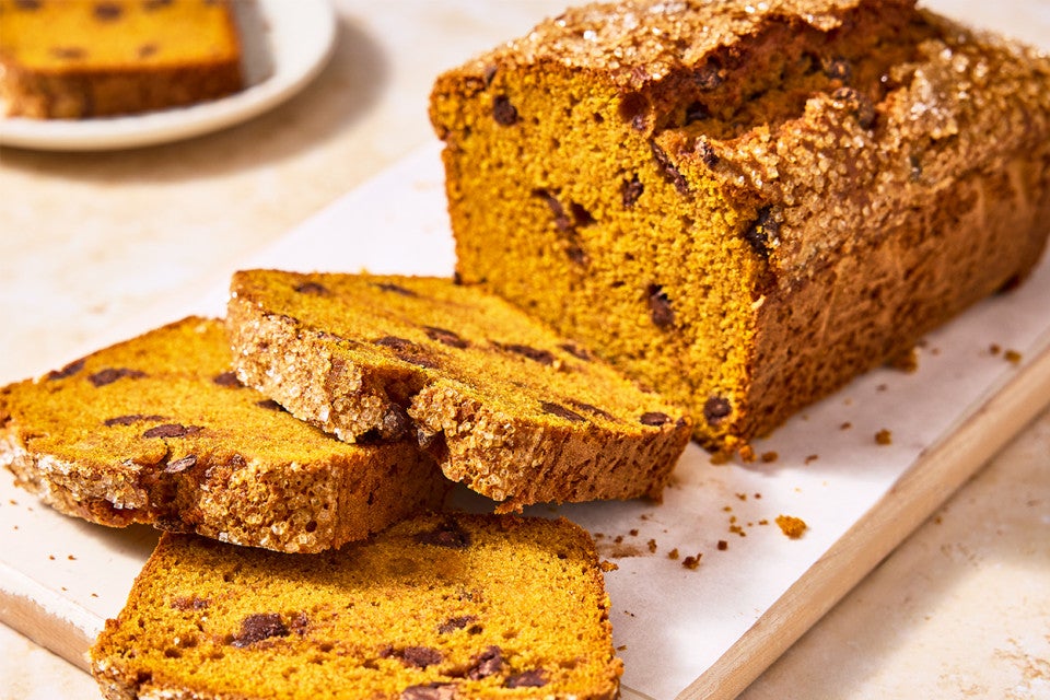 A loaf of The Most Pumpkin Pumpkin Chocolate Chip Bread with a few slices cut out of it