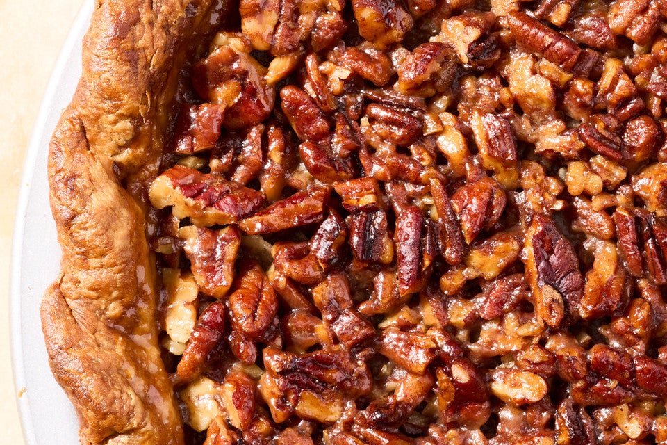 Detail of the surface of pumpkin pecan pie showing carmelized pecans and a flaky crust.