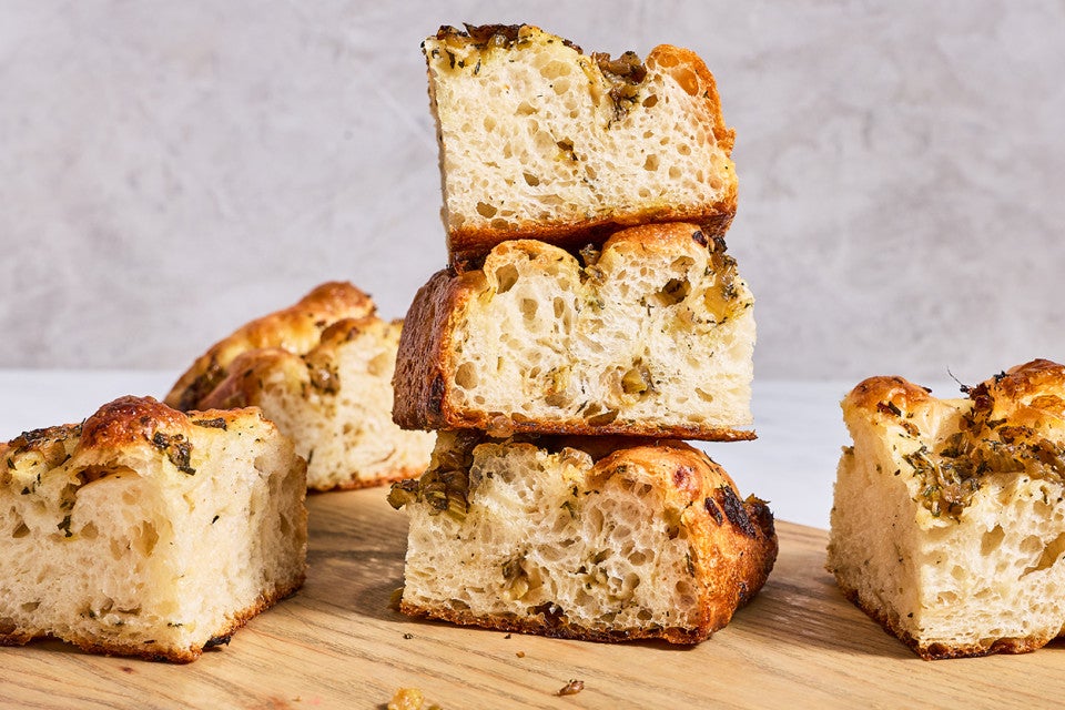 Focaccia chunks stacked and placed on a cutting board.