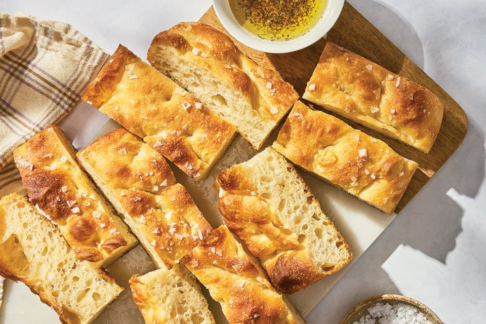 Sourdough Focaccia sliced on a cutting board with a dish of olive oil
