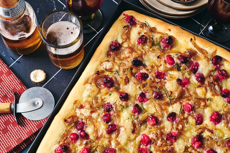 Caramelized Onion and Brie Pizza fresh out of the oven showing a golden baked top dotted with pomegranate, brie, and caramelized onion.