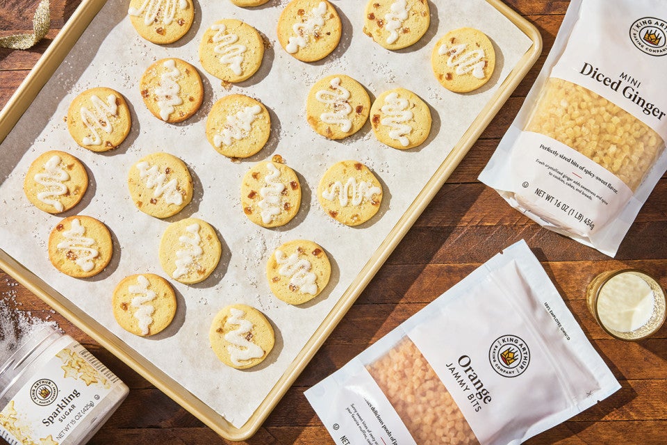 A sheet tray with Glazed Ginger-Citrus Shortbread spread out on parchment paper photographed from above.