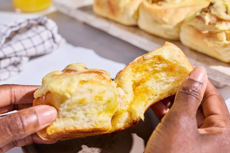 Pulling apart a Fluffy Frosted Orange Roll to show the light milk bread interior.