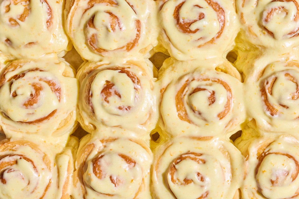 Detail shot of several Fluffy Frosted Orange Rolls together seen from above with a glossy yellow citrus glaze.