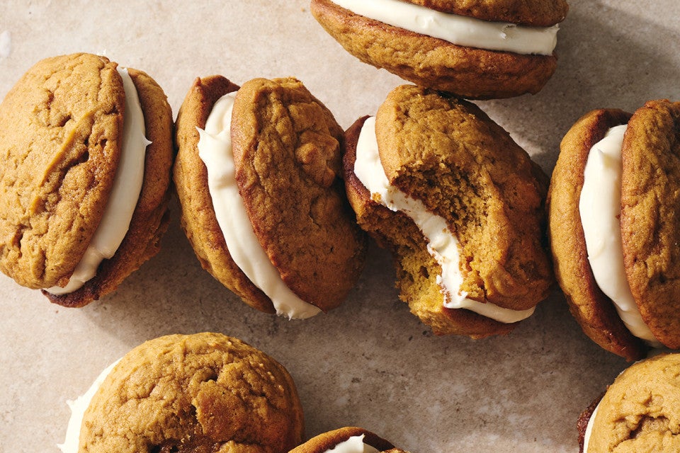 Pumpkin Whoopie Pies photographed together on a counter showing the layers of pumpkin cookie and creamy filling.