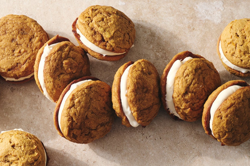 Pumpkin Whoopie Pies photographed together on a counter showing the layers of pumpkin cookie and creamy filling.