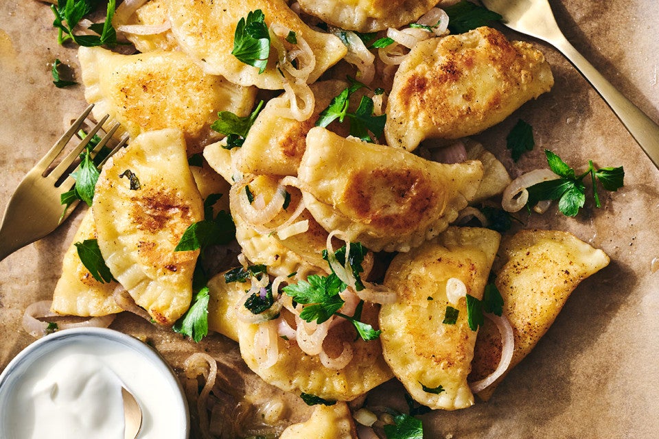 Homemade Pierogis on a plate with perfectly browned exteriors, garnished with herbs and onions.