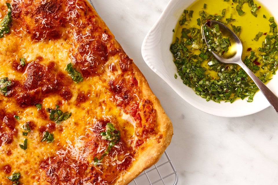 A full Flaky Puff Crust Pizza and a dish of basil oil