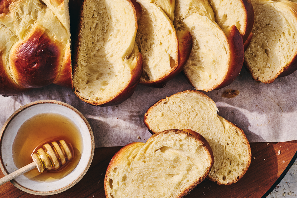 Challah bread sliced and shown on a counter with a bowl of honey next to the slices.