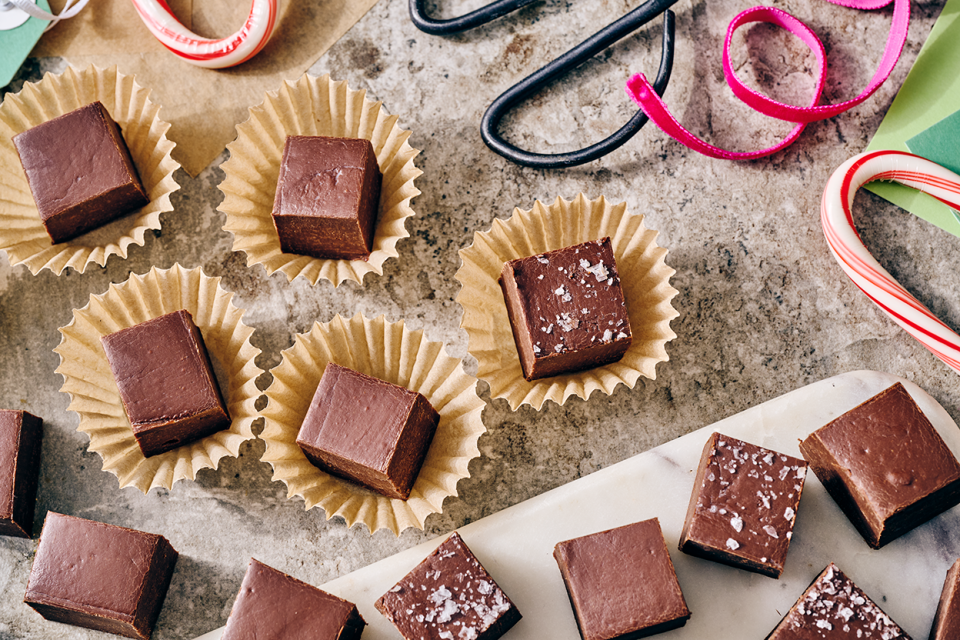 Easy Microwave Fudge cut into neat squares and placed in small paper cups with scissors and ribbon in the shot.