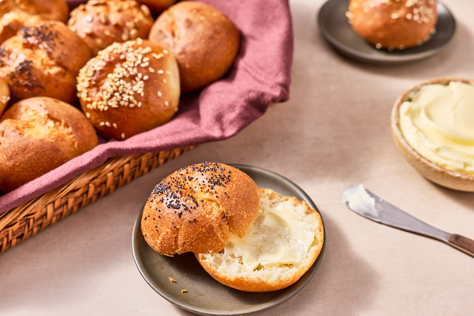 Various gluten-free buns and rolls shown in a basket and on plates.