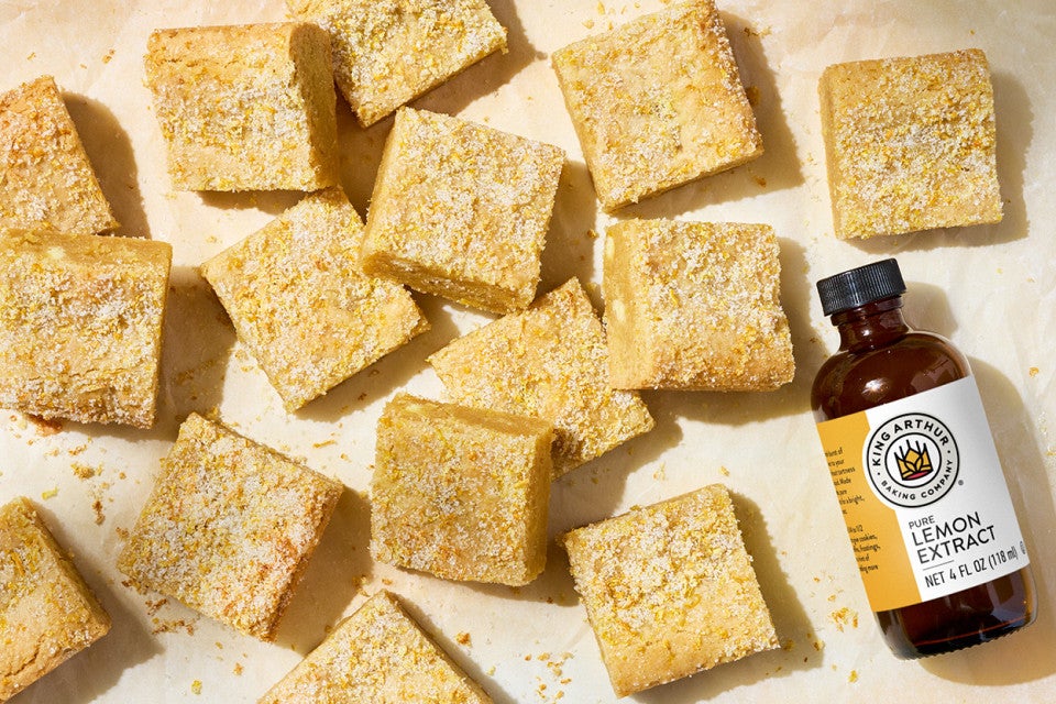Alex Roberts Lemon Citrus Blondies on parchment paper atop a counter with a bottle of pure citrus extract.