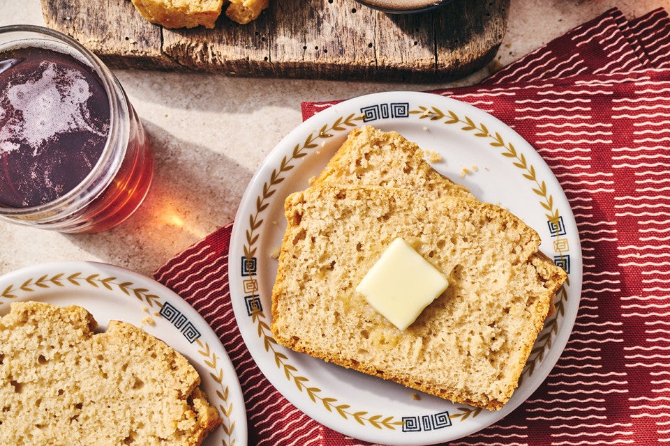 Sliced classic beer bread on a table with butter and a cutting board.