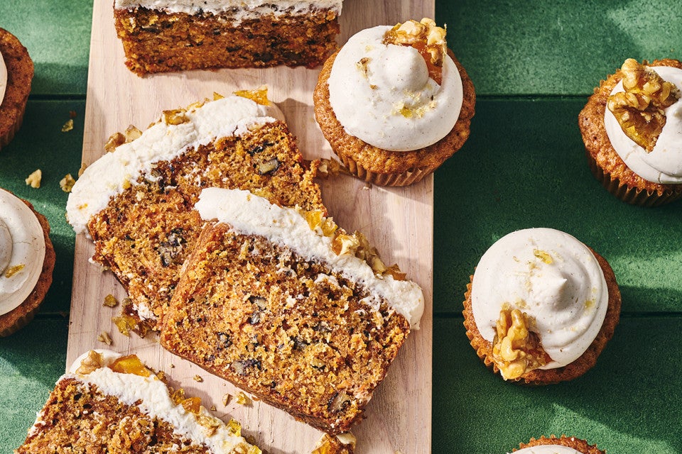 Spiced Carrot Snacking Cake on a cutting board with cupcakes around it.