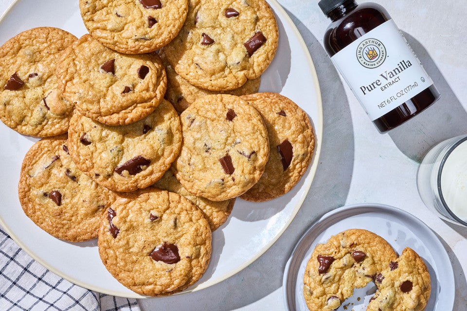 Cream Cheese Chocolate Chip Cookies arranged on a counter with King Arthur Vanilla shown on the counter.
