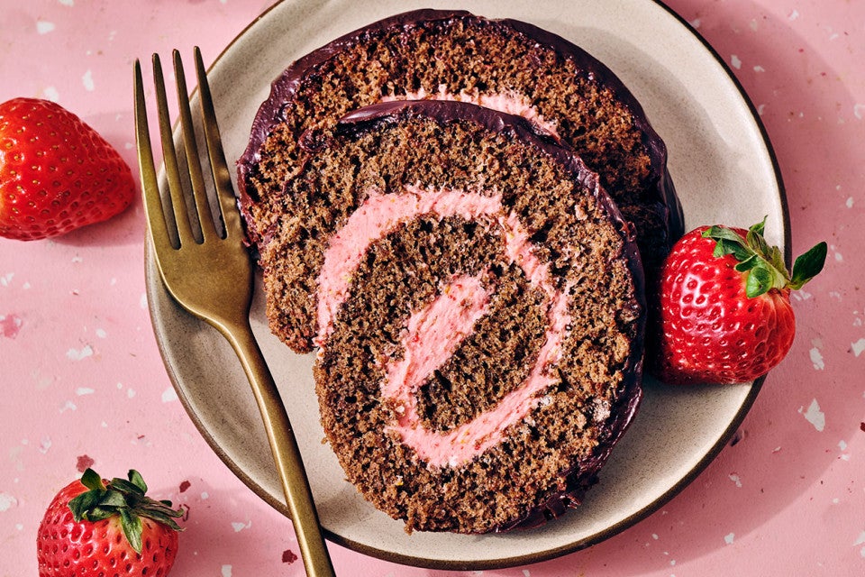 Chocolate Strawberry Roll Cake on a plate with a pink strawberry swirl clearly depicted in the cake.