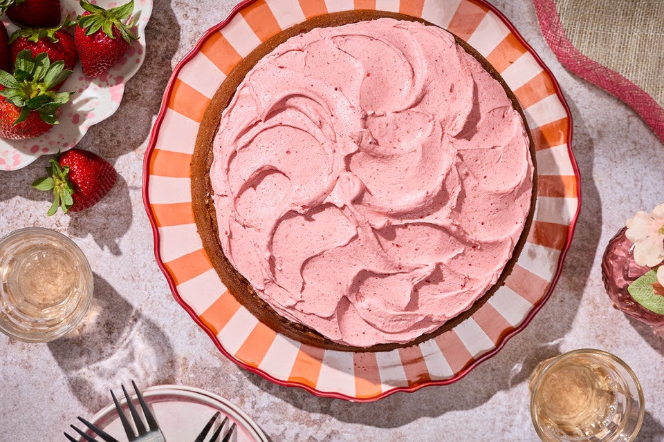 Brown Sugar Strawberry Frosted Cake on a table atop a striped plate