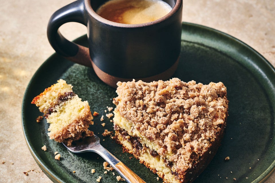 Cinnamon Streusel Coffee Cake on a dark green plate with a cup of coffee
