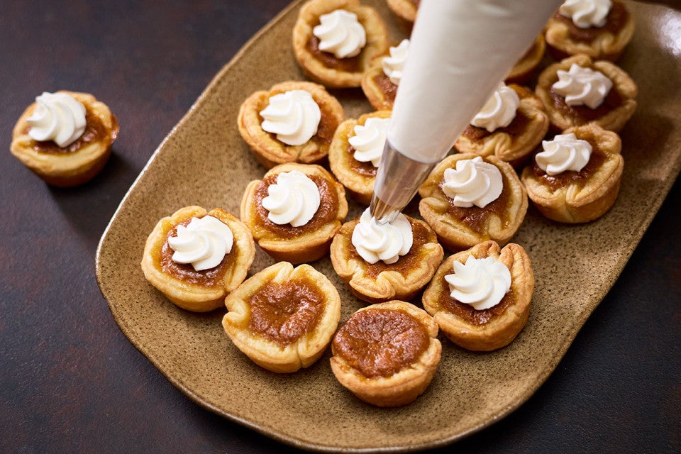 Adding whipped cream to the top of Mini Pumpkin Pies