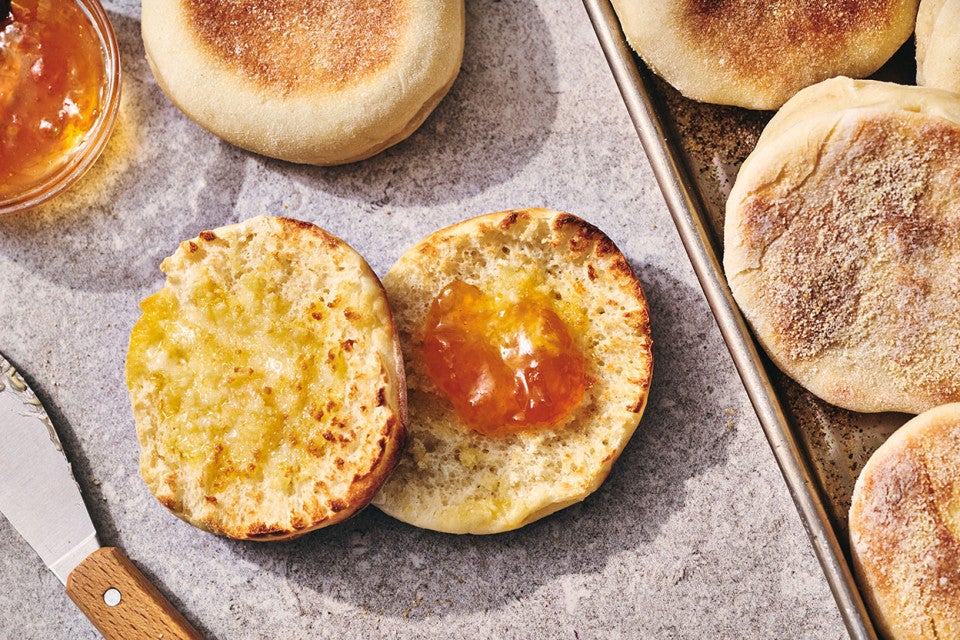 A Sourdough English Muffin sliced on a counter with butter on one half and jam on the other
