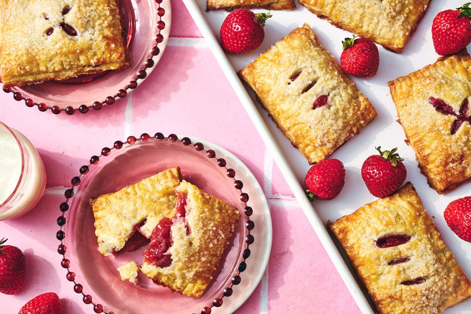 Strawberry Hand Pies on plates with one broken to show the strawberry filling