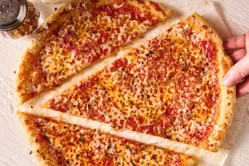 Removing a large slice of Gluten Free NY Style Pizza from the whole pie.