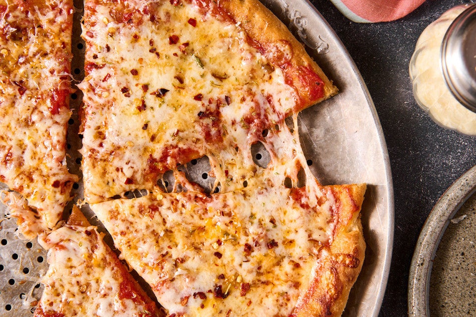 Gluten Free NY Style Pizza on a pizza pan seen from above.