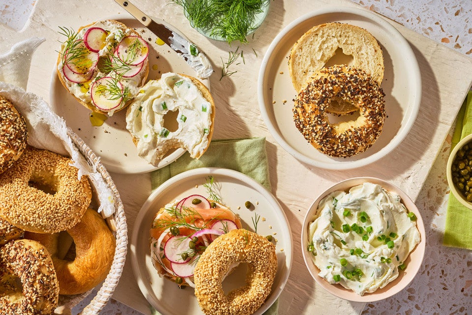 An arrangement of bagels on a counter with various spreads and toppings.