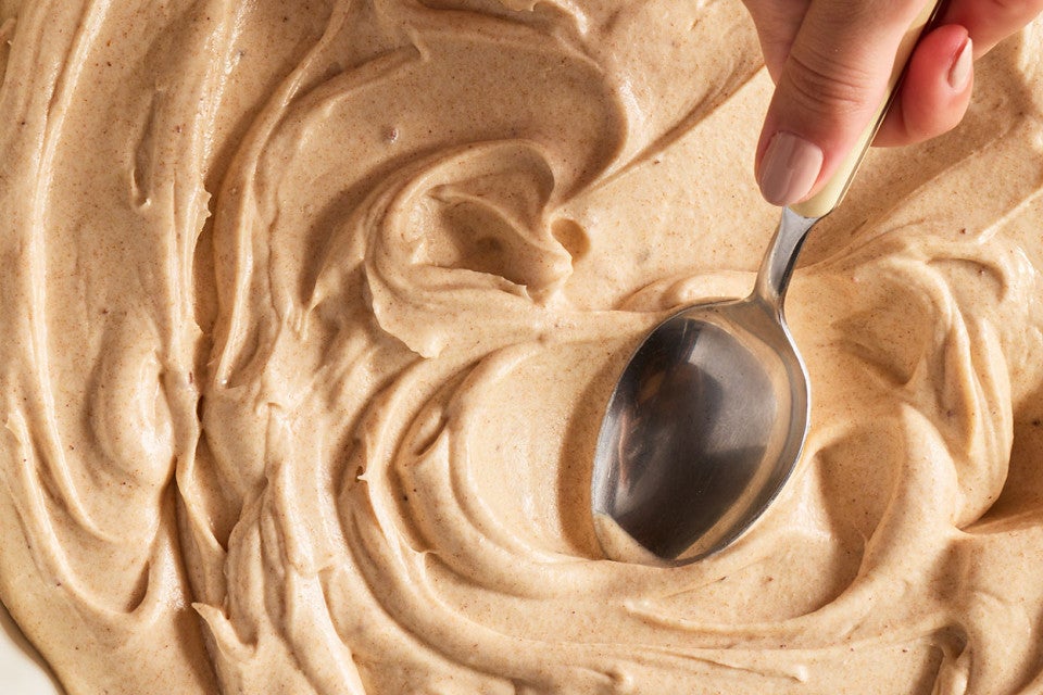 Swirling Brown Butter Cream Cheese Frosting with a spoon
