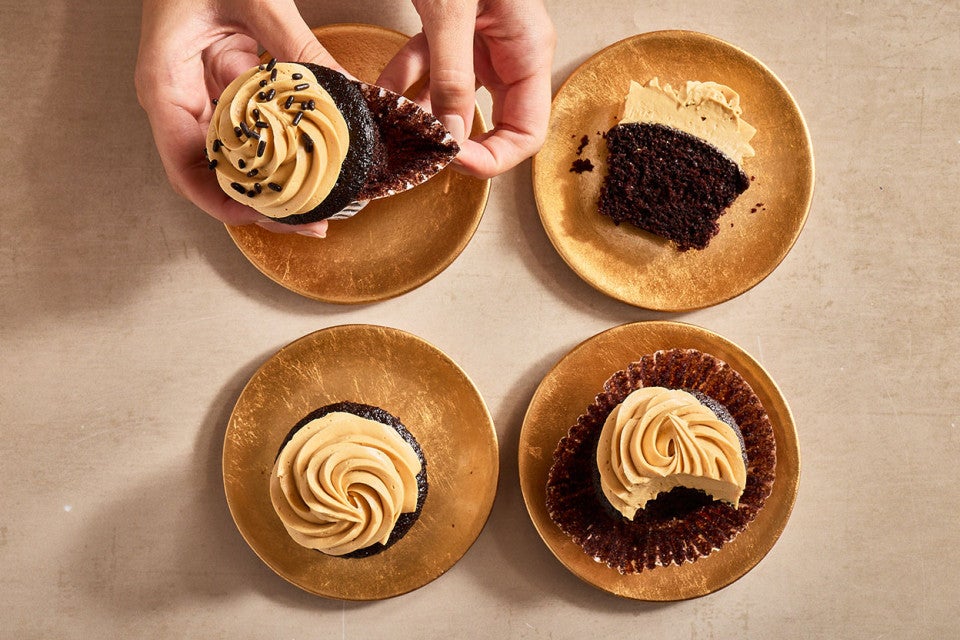 Peeling a cupcake wrapper from a Chocolate Cupcake with Whipped Caramel Frosting