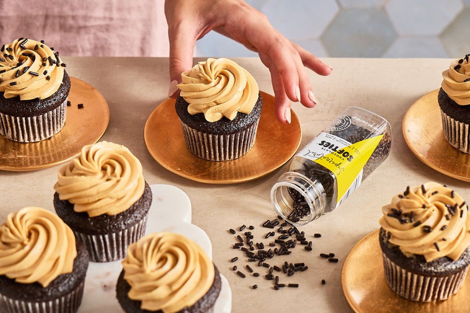 A table with Chocolate Cupcakes with Whipped Caramel Frosting atop it.