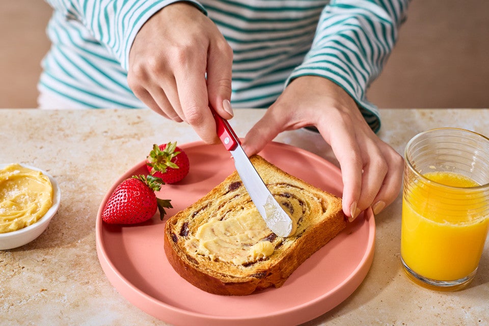 Spreading butter on a slice of Sourdough Cinnamon Swirl Bread