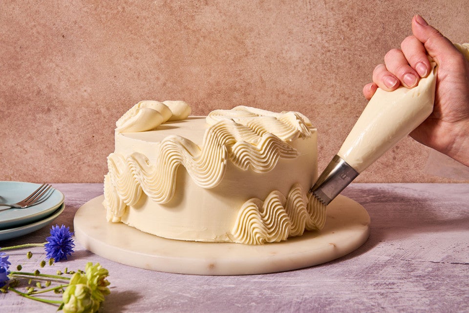 Piping Italian Buttercream onto a cake.