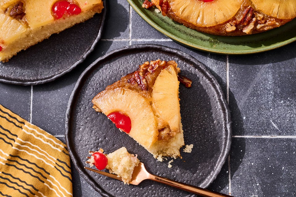 A slice of Pineapple Upside Down Cake on a plate with a bite on a fork seen from above.