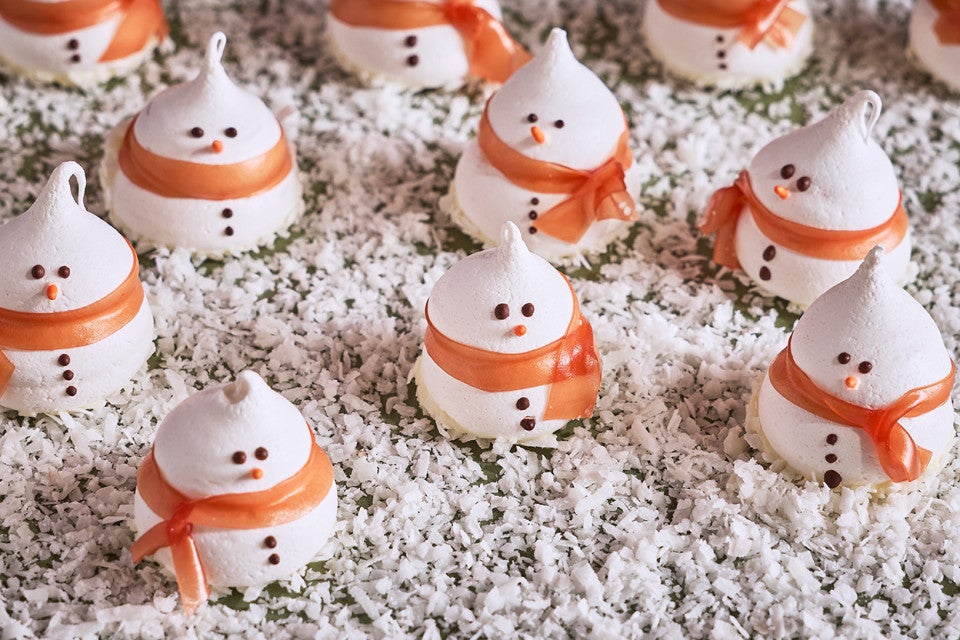 Snowman Meringues arranged on a counter with sugar snow