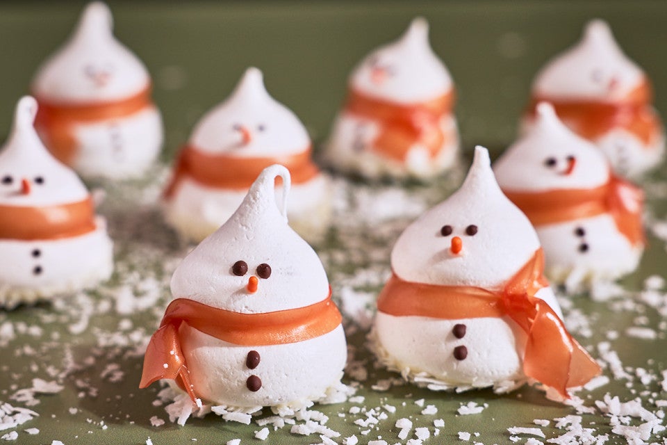 Snowman Meringues arranged on a counter with sugar snow