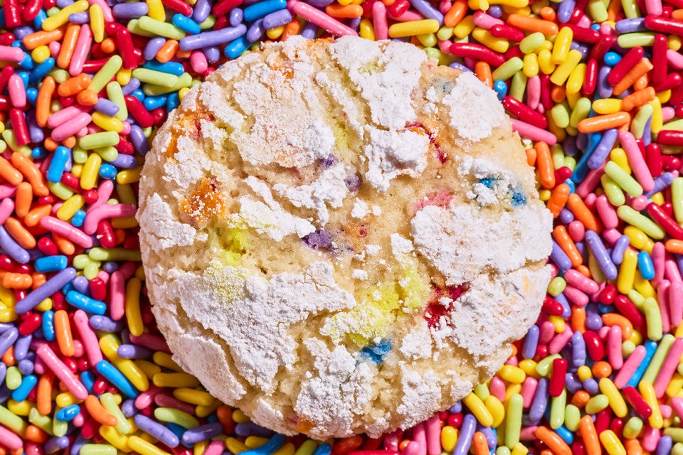 A Sprinkle Crinkle Cookie on a pile of colorful sprinkles
