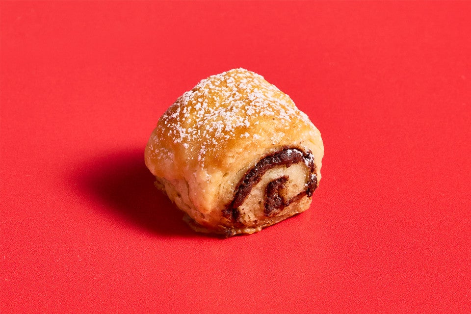 A single Chocolate Croissant Cookie on a red background