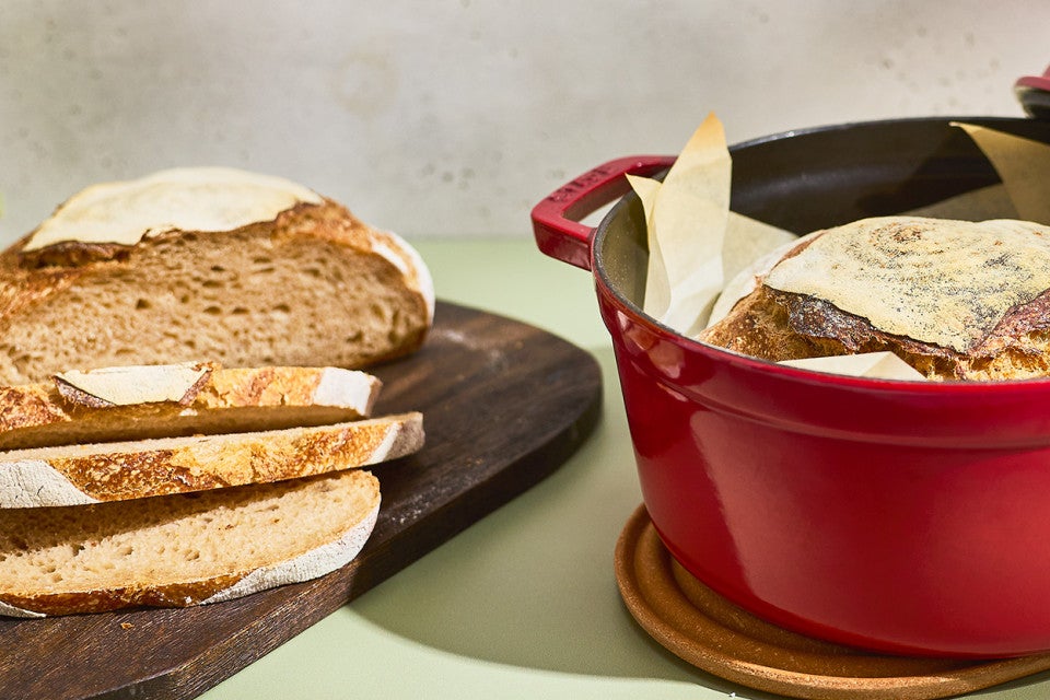 Crusty Dutch Oven Sourdough Bread sliced on a cutting board and shown in a dutch oven