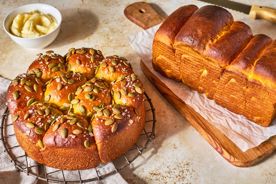 Pumpkin Milk Bread on a counter baked as rolls and a loaf of bread