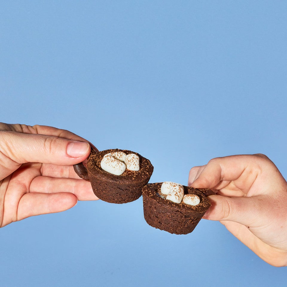 Tapping two hot cocoa cookies together in a cheers moment
