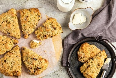 Zucchini scones on a piece of parchment paper with two on a small plate next to a bowl of butter