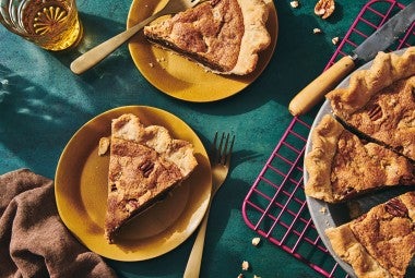 Slices of Chocolate Chip Pecan Pie on plates next to the full pie