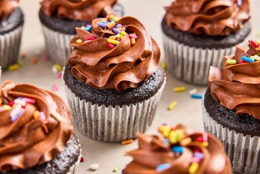 A bunch of Bake Sale Fudge Cupcakes topped with rainbow sprinkles