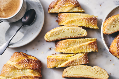 Cheese Filled Sweet Braid sliced on a counter with a cup of coffee in the corner.