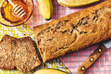 A loaf of Sourdough Banana Bread on a countertop with two pieces sliced and laying on their side.