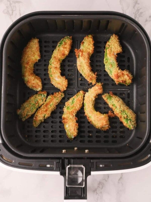 Cooked avocado fries in air fryer basket