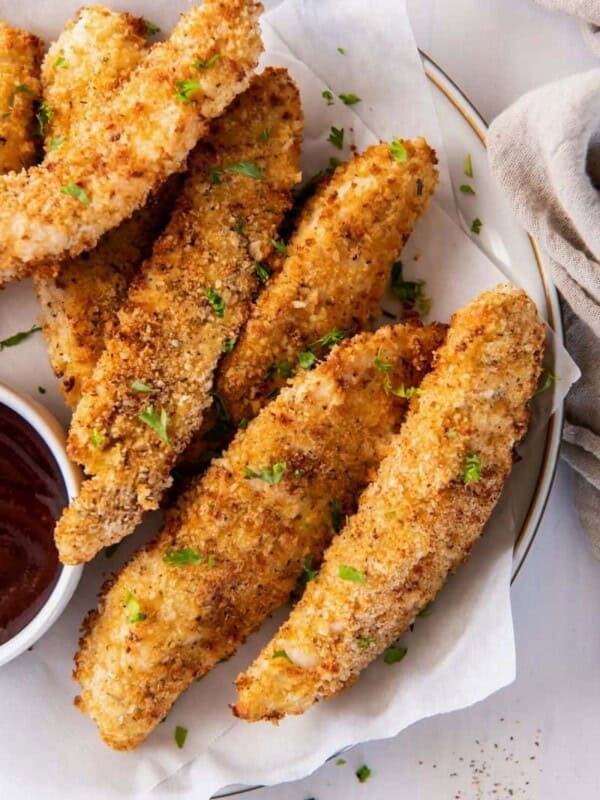 Panko breaded air fryer chicken strips on a serving plate with bbq sauce