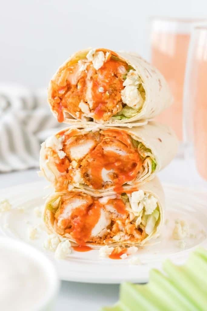 3 Buffalo chicken wraps stacked on top of each other cut in half on a white plate